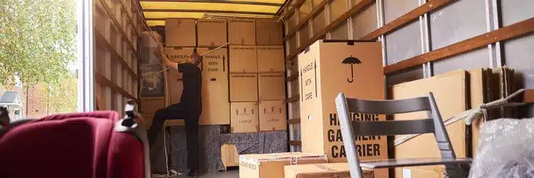 Verhuisdozen worden ingeladen in een bus bij een woning